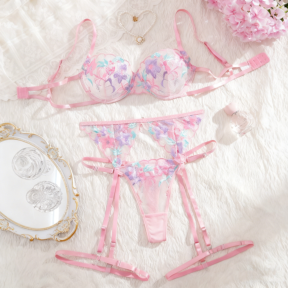 Pink floral lingerie set on a soft white surface with decorative items.