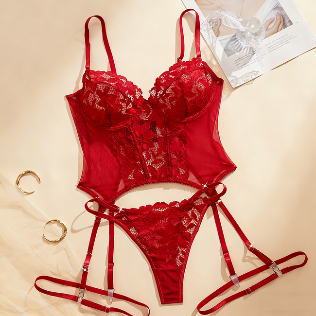 Red lace lingerie set on a beige background with a magazine. Hover Image