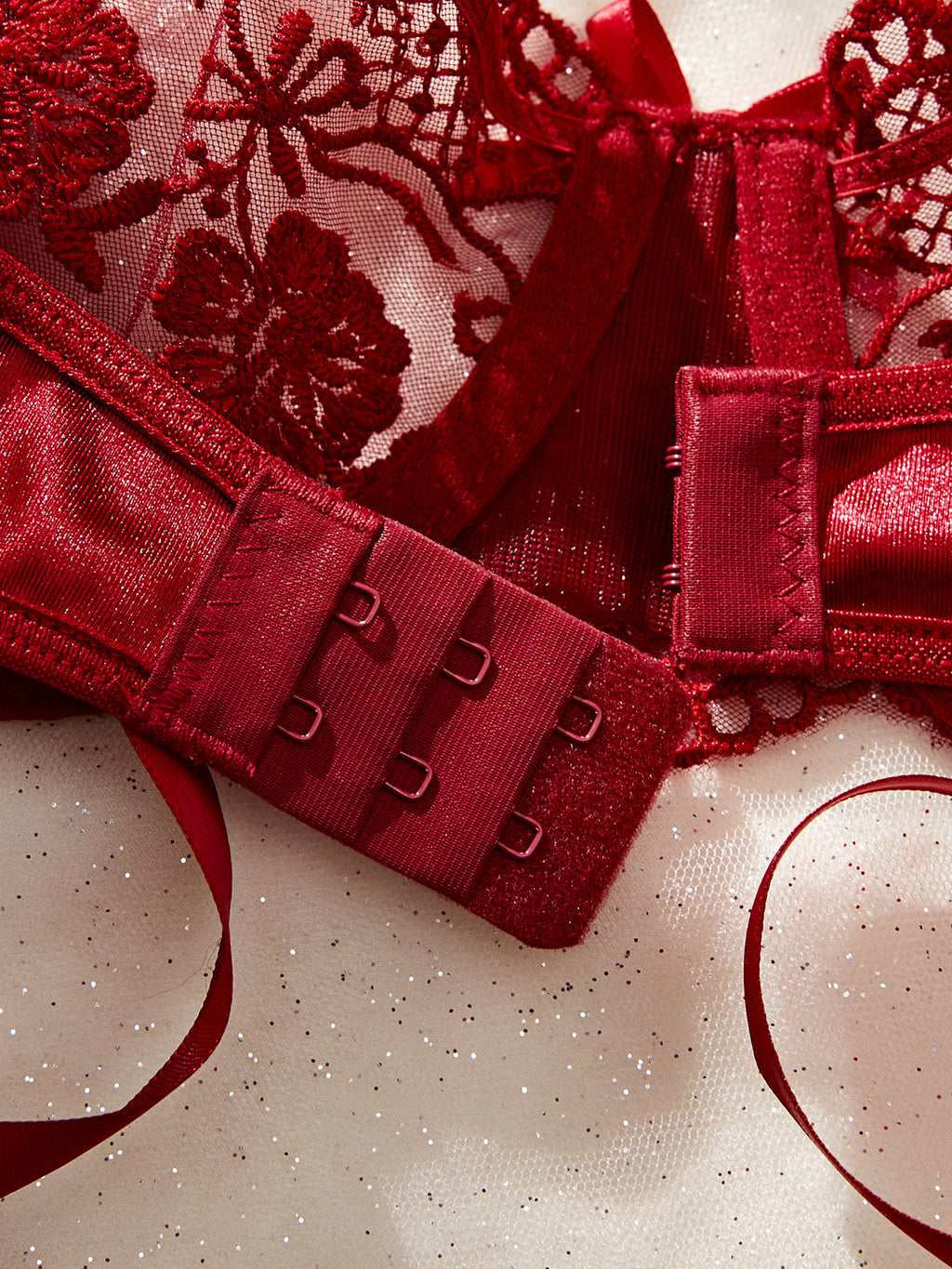 Red lace lingerie with floral embroidery on a textured surface