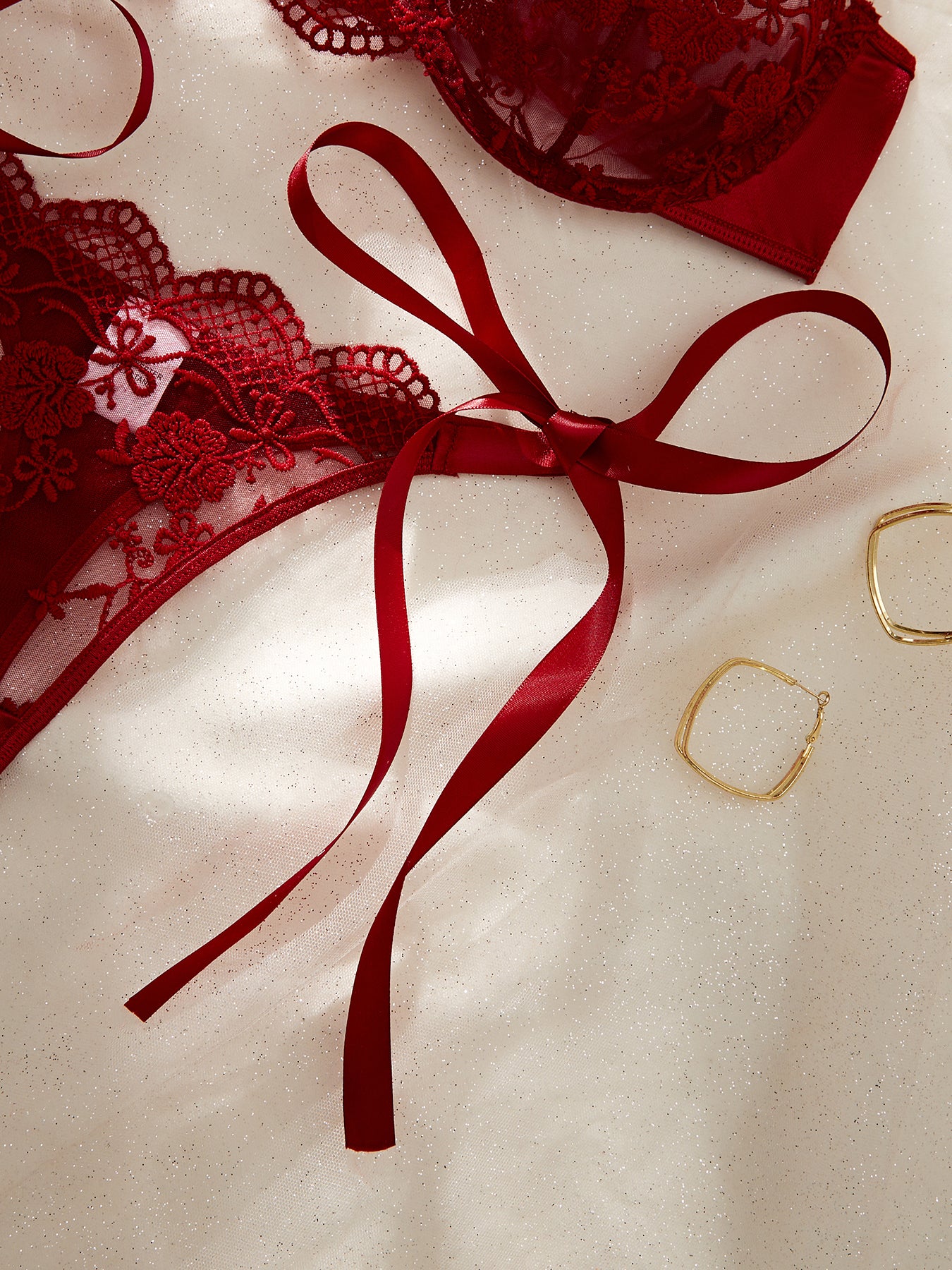 Red lace lingerie with a red ribbon on a beige background