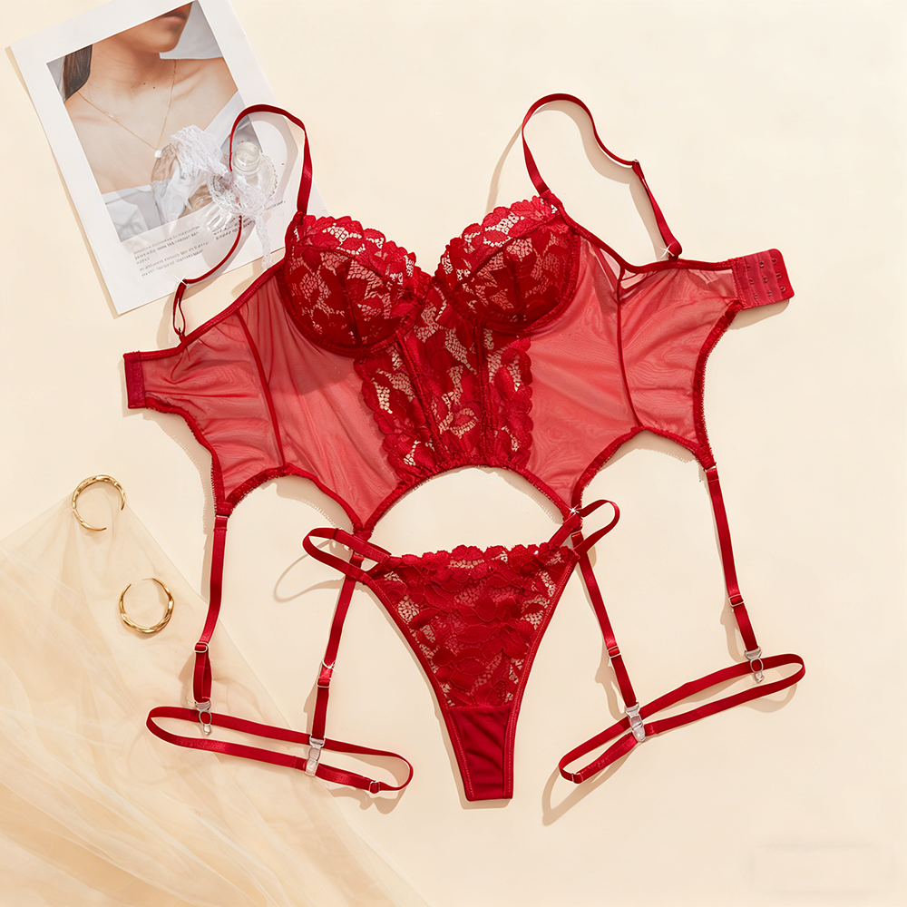 Red lace lingerie set on a beige surface with a magazine and gold ring.